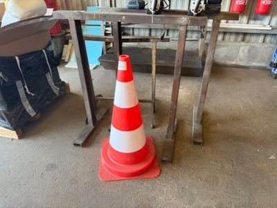 un cône de signalisation orange et blanc posé sur une table dans un garage