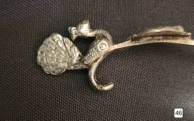 a silver brooch with a bird and a flower on it