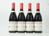 quatre bouteilles de vin rouge sont alignées sur une table