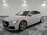une Audi blanche garée dans une grande pièce au sol à carreaux