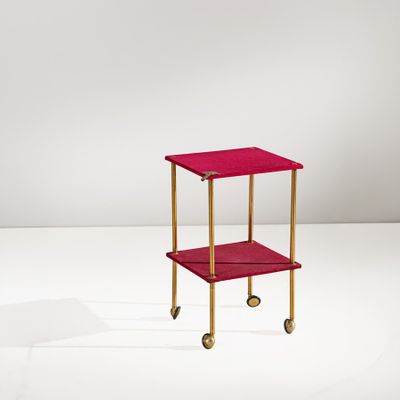 une image représentant une petite table rouge à roulettes posée sur une surface blanche
