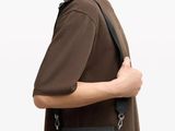 the man is wearing a brown shirt and a black bag
