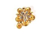 un gros plan d'une broche en forme de fleur en or, ornée d'un diamant au centre