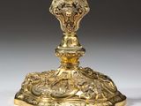 an ornate gold plated candle holder with a bird on top
