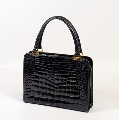 a black crocodile skin handbag on a white background