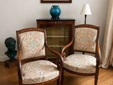 deux chaises dans un coin d'une pièce, avec un vase bleu sur la table