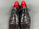 a pair of brown shoes with red soles sitting on a gray surface