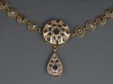 a close up of a gold necklace with a tear shaped pendant on it
