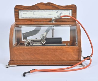 une boîte à musique à l'ancienne, munie d'un cordon rouge et d'un fil métallique