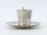 a silver cup and saucer on a saucer on a plate