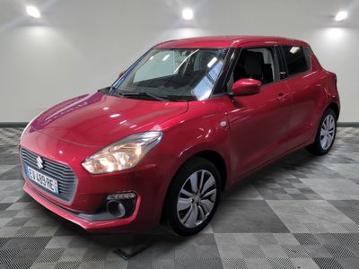the red suzuki swift is parked on a checkered floor
