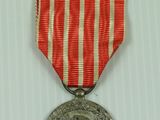 an old medal with a red and white ribbon on a white surface