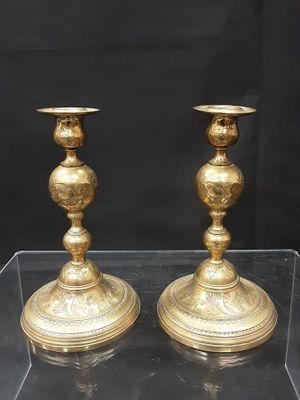une paire de bougeoirs anciens en laiton, présentés dans une vitrine en acrylique transparent