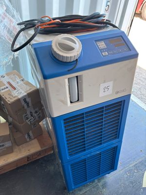 un climatiseur bleu et blanc posé sur une palette à côté de quelques cartons