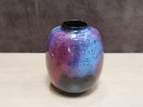 a purple and blue vase sitting on a wooden table
