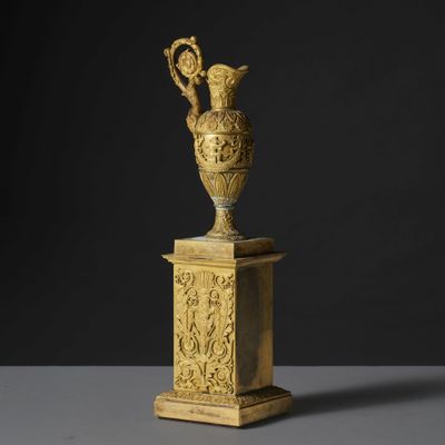 un vase en or posé sur un socle, sur fond noir