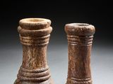 une paire de bougeoirs en bois sculpté posés sur un support gris