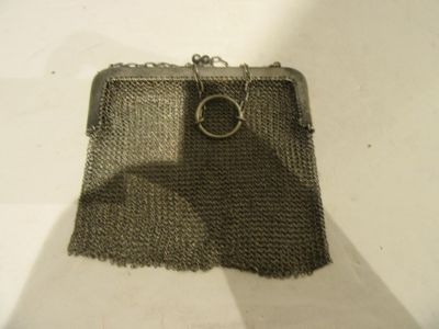 un porte-monnaie en argent muni d'un anneau, posé sur une table