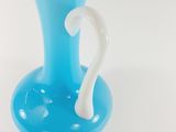a blue vase with a white handle sitting on a table