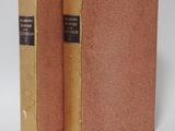 two old books sitting on top of each other on a white surface
