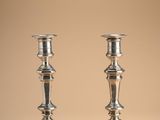 pair of silver candlesticks on a beige background