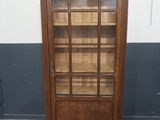 une vieille armoire en bois avec des portes vitrées et des étagères, dans une pièce