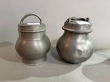 two silver pots sitting next to each other on a table