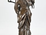 bronze statue of a woman with a bow on a wooden base