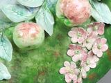 a green plate with flowers and apples on it