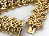 a close up of a gold bracelet on a white surface