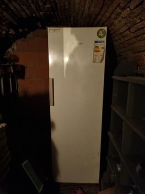 a white refrigerator in a dark room with a brick wall