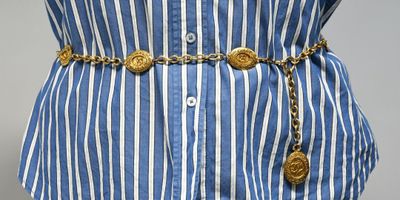 un gros plan sur la taille d'une femme portant un t-shirt rayé bleu et blanc, avec une ceinture dorée