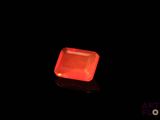 an orange diamond in the dark with a reflection on the ground
