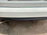 the back end of a white car with a sticker on it ' s bumper