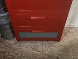 a red chest of drawers in the corner of a room