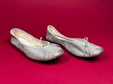 pair of silver ballet shoes on a red background