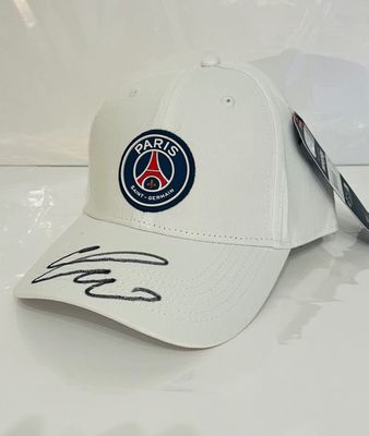 La casquette est blanche et comporte un écusson bleu sur le devant.