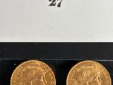 two gold sovereigns in a display case on a black surface