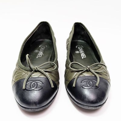 une paire de chaussures noires et vertes à lacets posées sur une surface blanche