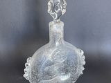 une bouteille en verre transparent surmontée d'un oiseau