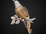 une broche en forme d'oiseau en or et diamants, posée sur une branche