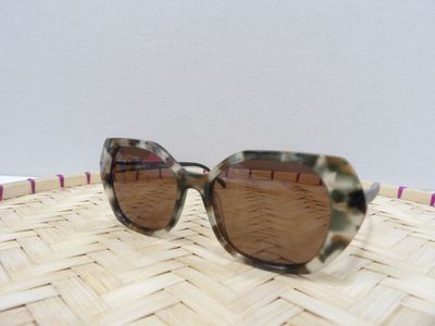 un gros plan sur une paire de lunettes de soleil posée sur un panier tressé
