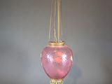 a pink glass lamp hanging from a gold chain