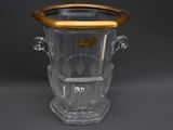 vase en verre transparent avec un bord et des anses dorés sur un fond gris