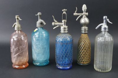 six bouteilles en verre de couleurs différentes sont alignées sur une surface noire