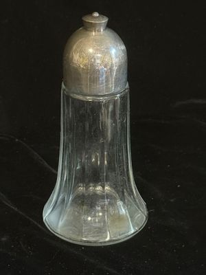 une cloche en verre transparent avec un couvercle argenté sur fond noir