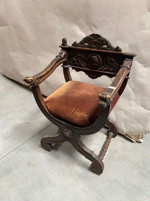 une vieille chaise en bois avec une assise rouge, posée sur un sol en béton
