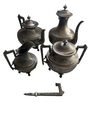 trois théières en argent et une théière posée sur un socle
