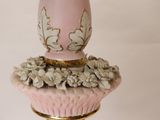 a pink vase on a gold stand with flowers on it