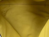 the inside of a yellow handbag with a black handle